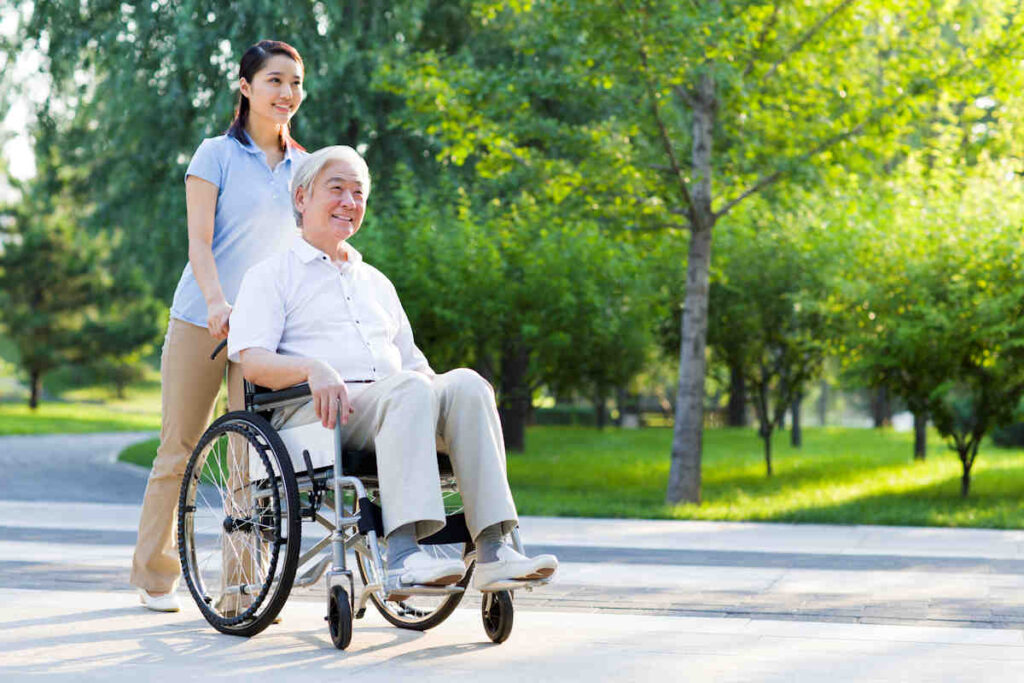 Ayudante paseando hombre silla de ruedas