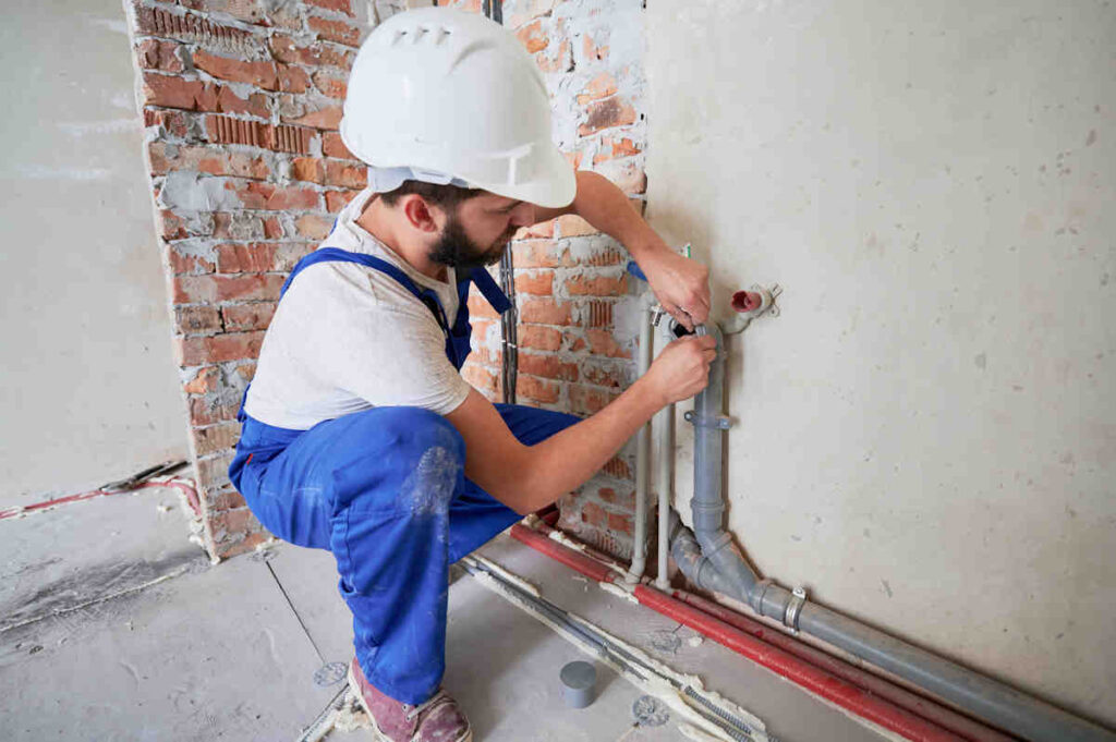 Fontanero de obra arreglando tubería.