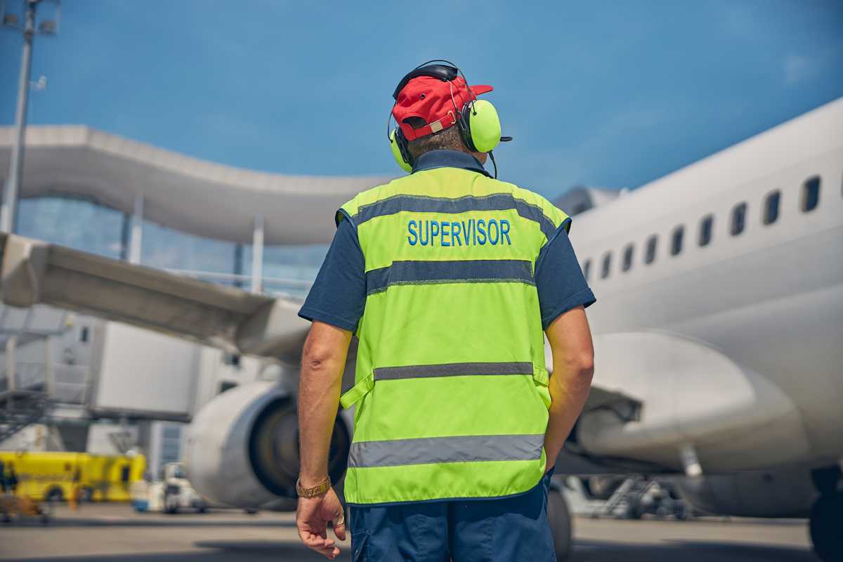 Supervisor aeropuerto de espaldas, atendiendo al avion